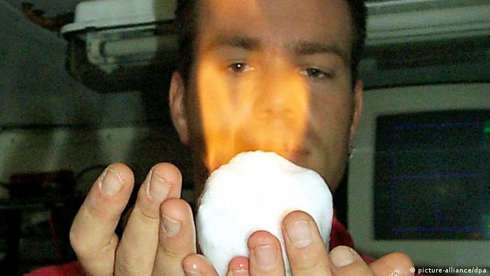 Ein Mann hält einen brennenden Klumpen Methanhydrat in seinen Händen (Foto: dpa/lby)
