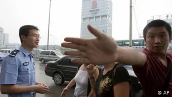 A plainclothes officer at right tries to prevent a photographer from taking a photo of a Chinese police officer questioning two journalists near the headquarters of the Beijing Olympics planning committee seen in the background in Beijing, China, Monday, Aug 6, 2007. Police roughed up journalists at a rare protest Monday in Beijing, staged by Reporters Without Border, the free-press advocacy group that accuses the government of failing to meet promises for greater media freedom one year ahead of the 2008 Olympic Games. (ddp images/AP Photo/Ng Han Guan)
