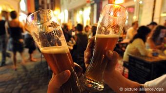 Zwei Männer stoßen mit Weizenbiergläsern an.