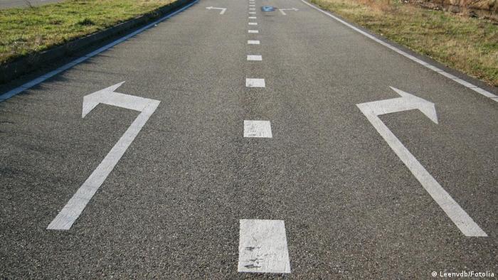Eine Straße mit zwei Pfeilen, die verschiedene Richtungen anzeigen. Arrows pointing in opposite direction before fork in road. Erstellung: 02.02.2012 © Leenvdb #11885373