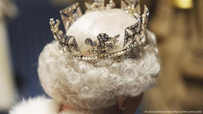 Back of head of Queen Elizabeth II wearing a crown in curly white hair 