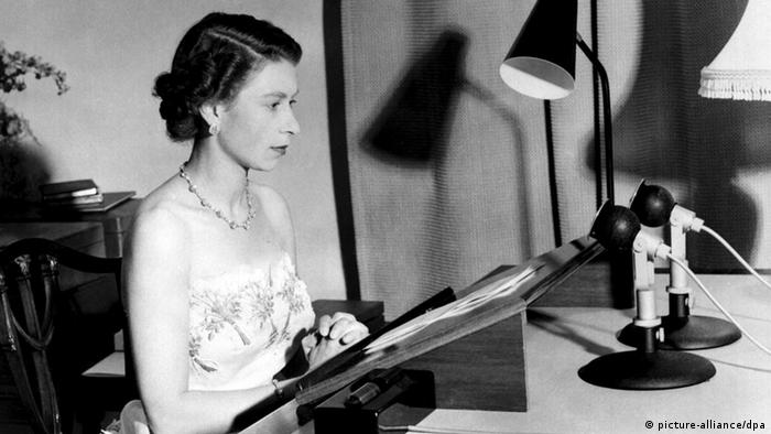 Königin Elisabeth II auf einer schwarz-weiß Fotografie vor einem Rednerpult und zwei Mikrofonen.