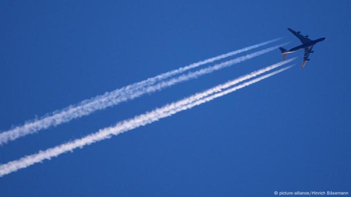 Flugzeug mit Kondensstreifen an einem blauen Himmel