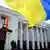 Люди с украинскими флагами рядом со зданием парламента в Киеве
