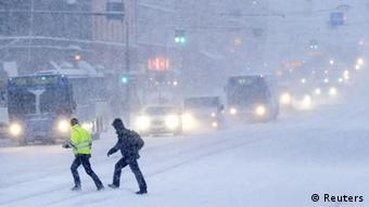 People make their way across a road during heavy snowfall in downtown Helsinki February 3, 2012.