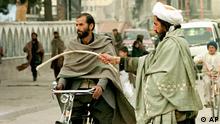 A Taliban soldier instructs a bypasser to go to pray in a mosque in Kabul Friday, Nov. 29, 1996. The Taliban, a band of religious students and clerics, controls two-thirds of Afghanistan and has been locked in a fierce battle against the alliance since capturing Kabul on Sept. 27. The religious army began fighting three years ago and has imposed a strict version of Islamic law in areas it controls, forbidding women from working and forcing men to attend prayer services five times a day. (AP Photo/Dimitri Messinis)