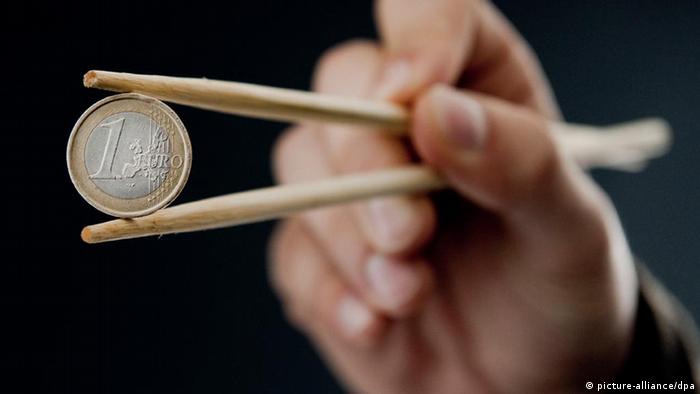 Монета евро, зажатая китайскими палочками 