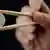 A euro coin held symbolically by a pair of Chinese chopsticks