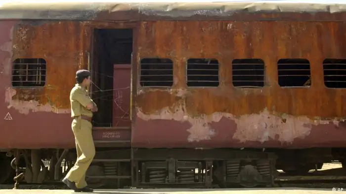 An unidentified policeman walks past the burnt S-6 coach of Sabarmati Express train at Godhra, India, Tuesday Feb. 25, 2003. Mosques, Hindu temples, train and bus stations in the western state of Gujarat will come under heavy police guard on Thursday, Feb. 27, 2003, the anniversary of a train attack that triggered India's worse religious violence in a decade. (AP Photo/Siddharth Darshan Kumar)