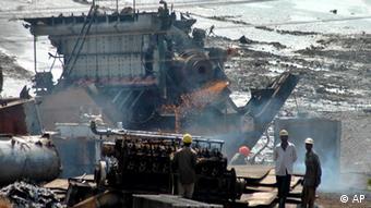 Arbeiter vor und auf einem riesigen Stahlteil aus einem Schiffswrack (Foto: AP)