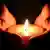 Foto simbólica de unas manos con una candela encendida en símbolo de luto.