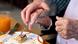 Hand eines Pflegers, der einem alten Menschen hilft, beim Essen die Gabel zu führen Hand eines Pflegers, der einem alten Menschen hilft, beim Essen die Gabel zu führen