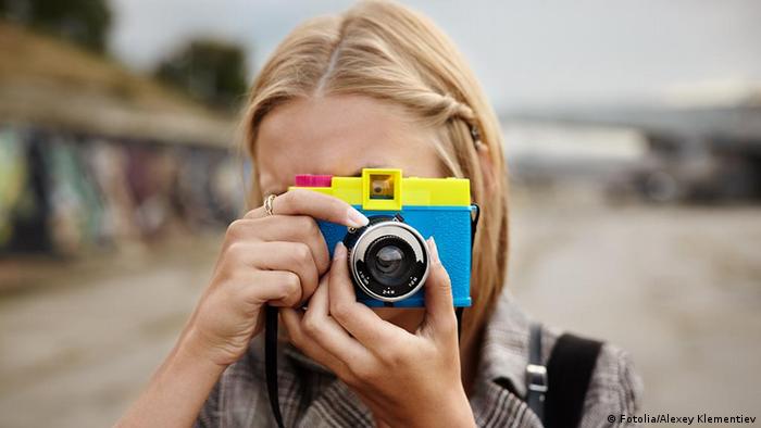 Foto simbólica de una persona con una cámara fotográfica en una imagen de archivo.