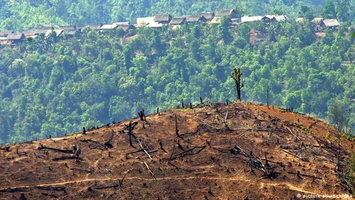 A small village where rice and opium farmers live is seen behind a large hill which has been cleared of timber by slash and burn methods ready for agriculture, in north-eastern Myanmar (Burma), close to the Chinese border, Monday 26 April 2004. Unchecked logging fuelled by the huge growth in the Chinese economy has taken its toll on the area. Deforestation is acute in Myanmar as a consequence of timber exploitation and poor agricultural methods and it is one of the least environmentally protected countries in South East Asia. Myanmar supplies 60 per cent of the world's teak wood consumption, and derives nearly 10 percent of it's foreign income from timber exports. Foto: BARBARA WALTON dpa