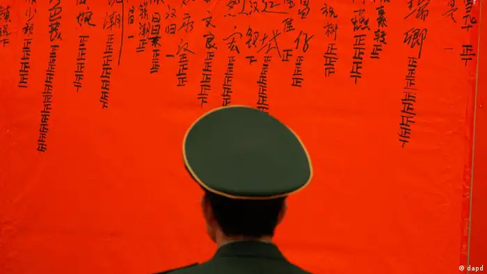 A Chinese police officer guards in front of a board to show result of counting votes for the candidates during an election to select village committees at a polling station in Wukan village, Lufeng city, south China's Guangdong province, Saturday, March 3, 2012. Villagers who rebelled against officials they accused of stealing their farmland voted for new leaders on Saturday in a much-watched election reformers hope will promote democracy as a way to settle many of the myriad disputes besetting China. (Foto:Vincent Yu/AP/dapd)