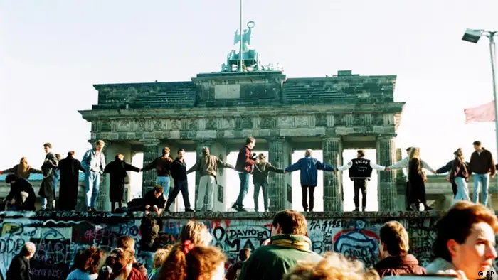 Dancing On The Wall - Berliners sing and dance atop the wall to celebrate the opening of East-West German borders November 10. Thousands of East German citizens moved into the West after East German authorities opened all border crossing points to the West. In background is the Brandenburg gate. (AP Photo/Thomas Kienzle/str) 10. November 1989