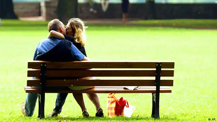 Ein Paar küsst sich auf einer Parkbank