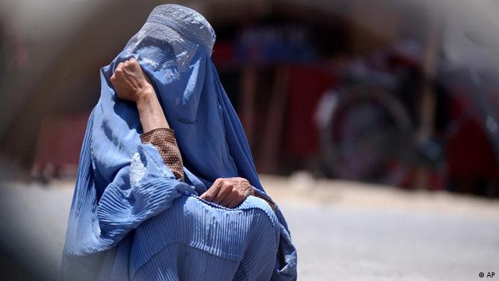 An Afghan woman in veil waits for a bus at a bus stop in Kabul, Afghanistan