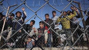 Flüchtlinge stehen hinter dem Zaun eines Auffanglagers in Kyprinos, Griechenland (Foto: Nikos Arvanitidis / epa dpa)
