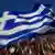 Die griechische Flagge weht hinweg über die Kopfe vieler Griechen (Foto: DPA)