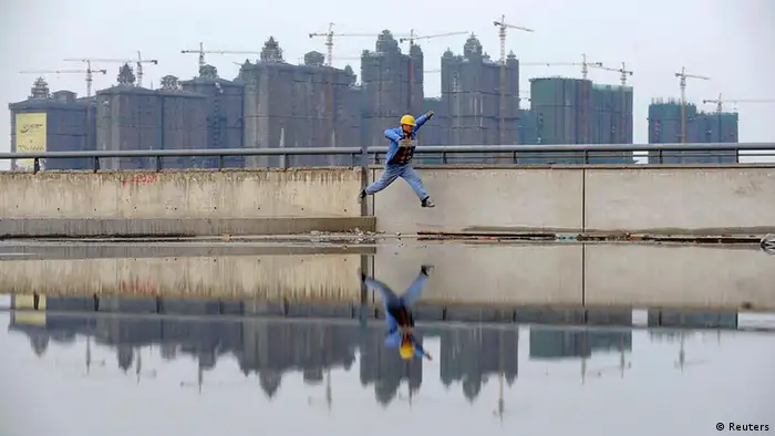 A worker jumps over a puddle near a residential construction site in Taiyuan, Shanxi province in this October 26, 2010 file photo. Global investors worried about a cut to China's official economic growth forecast to 7.5 percent this year would do well to remember the maxim of asset strippers everywhere: the sum of the parts is worth more than the whole. To match Analysis CHINA ECONOMY/GROWTH. REUTERS/Stringer (CHINA - Tags: BUSINESS IMAGES OF THE DAY) CHINA OUT. NO COMMERCIAL OR EDITORIAL SALES IN CHINA