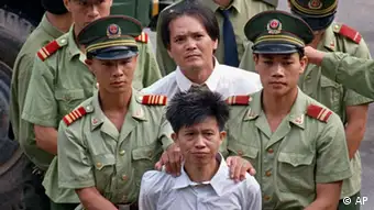 ** FILE **Wang Shijian, from China, foreground, and Hong Kong resident Wong Tin-soong are led by police officers into a stadium in Shenzhen, China, to hear the public announcement for their death sentences for drug-related convictions in this Aug. 15, 1996 file photo. The two, along with eight other men were later taken to a remote location in the suburb where they were executed by gunshots. China, the world's leading executioner of prisoners, should reduce the number of death sentences it carries out but cannot abolish capital punishment altogether, the country's top legal bodies said during the ongoing National People's Congress. (AP Photo/Vincent Yu, File)