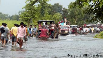 Nach heftigen Monsun-Regenfällen bahnen sich in der Nähe von Madhurganj in Indien Einwohner ihren Weg durch überflutete Straßen(Foto: dpa)