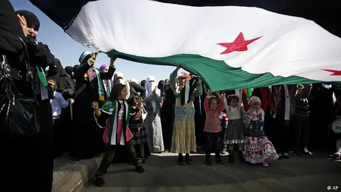 Syrian protesters chant anti-Bashar Assad slogans under a large revolutionary flag during a protest in front the Syrian embassy in Amman, Jordan, Friday, March 9, 2012. Hundreds of Syrians attend the Friday prayer, prior to a protest in front the Syrian embassy to demand International intervention and to arm the Free Syrian Army. (AP photo/Mohammad Hannon)