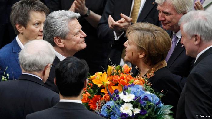 Joachim Gauck receives flowers from Chancellor Angela Merkel after he was elected German president at Germany's Federal Assembly in Berlin, March 18, 2012. German lawmakers elected Joachim Gauck, a former Lutheran pastor and human rights activist from communist East Germany, as president of the European Union's largest country on Sunday by a large majority in a first round of voting. REUTERS/Thomas Peter (GERMANY - Tags: POLITICS ELECTIONS)