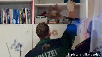 Ein Polizist durchsucht ein Regal nach Neonazi-Propaganda (Foto: dpa)