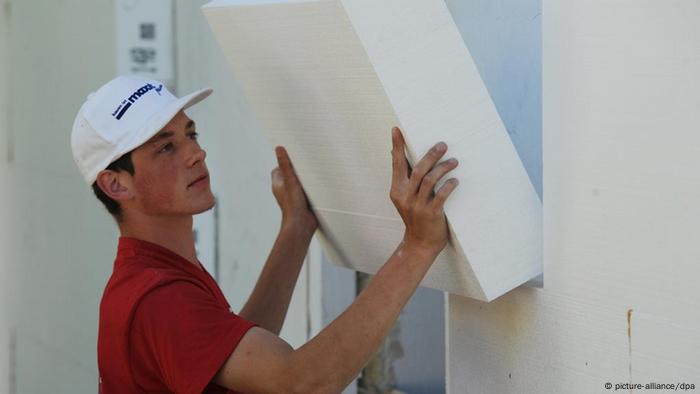 Ein Mann montiert eine Styroporplatte zur Wärmedämmung an eine Fassade in Straubing Foto: Armin Weigel