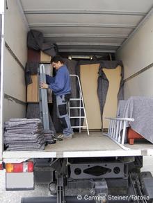 Ein Möbelpacker arrangiert in einem Umzugs-LKW Sachen