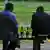 Два человека распивают пиво на скамейке
