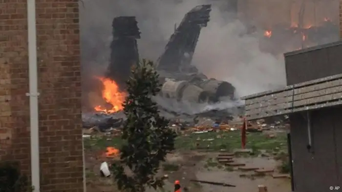 The burning fuselage of an F/A-18 Hornet lies smoldering after crashing into a residential building in Virginia Beach, Va., Friday, April 6, 2012. The Navy did not immediately return telephone messages left by The Associated Press, but media reports indicate the two aviators were able to eject from the jet before it crashed. They were being treated for injuries that were not considered life threatening. (AP Photo)