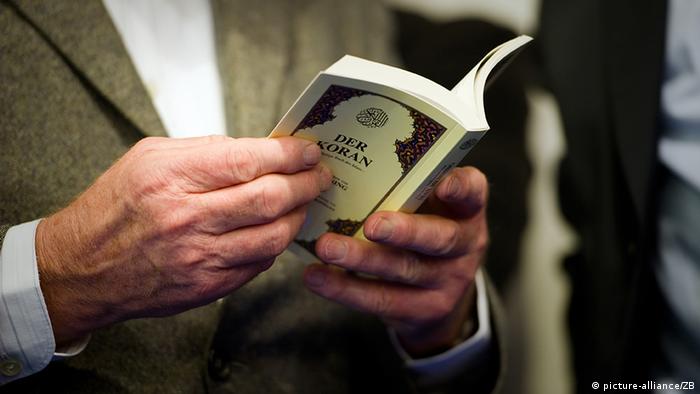 Ein Mann hält ein Buch mit der Aufschrift Koran in den Händen (Foto: Arno Burgi)