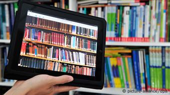 Ein iPad Tablet mit einer Bücherwand auf dem Bildschirm, im Hintergrund ein Bücherregal. Foto: Marc Tirl dpa