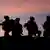 Silhouettes of soldiers against a sunset in Afghanistan © veneratio