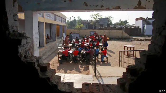 Indian school children attending a class are seen through a damaged wall at a government school in the outskirts of Jammu, India, Thursday, Dec.2, 2010.Indian technology mogul Azim Premji has announced he will donate nearly $2 billion to fund education and development programs in India's villages in one of the largest charitable donations in the country's history.(ddp images/AP Photo/Channi Anand)