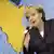 Chancellor Merkel is speaking in front of a large map of Africa.