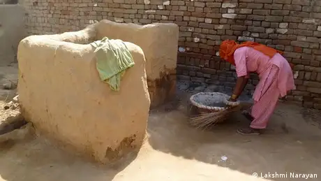 A woman prepares to clean a dry latrine in a poor farmer's house in Mudali