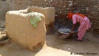 Manual scavenger woman preparies for cleaning a dry latrine in a poor farmer's house