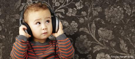 portrait of a handsome kid listening to music looking up against a vintage brown wall aged; attractive; audio; baby; background; boy; cheerful; child; childhood; cute; decay; dirty; enjoy; equipment; expression; eyes; face; fun; grunge; happiness; happy; head; headphones; human; joy; kid; leisure; listen; listening; little; looking; male; music; old; person; portrait; retro; rough; sing; small; smile; song; sound; technology; texture; urban; vintage; wall; white; young