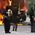 Linke Politgewalttäter stehen am 1. Mai in Hamburg vor einem brennenden Auto (Foto: dpa)