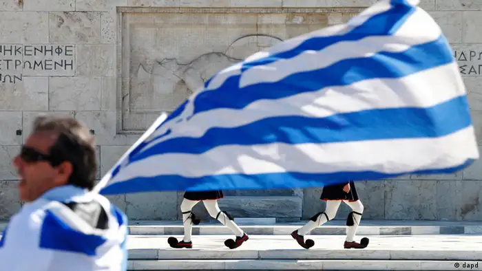 ARCHIV: Ein Mann schwenkt am Syntagma-Platz in Athen (Griechenland) die griechische Flagge, waehrend die als Evzones bezeichneten Wachen im Hintergrund am Grab des unbekannten Soldaten vorbei gehen (Foto vom 20.10.11). Am Sonntag (06.05.12) wird in Griechenland ein neues Parlament gewaehlt. (zu dapd-Text) Foto: Lefteris Pitarakis/AP/dapd