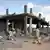 Libyan men walk past destroyed buildings on August 10, 2011, in Majer