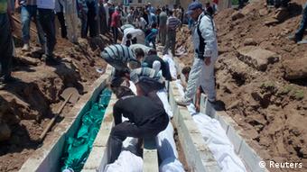 People gather at a mass burial for the victims purportedly killed during an artillery barrage from Syrian forces in Houla