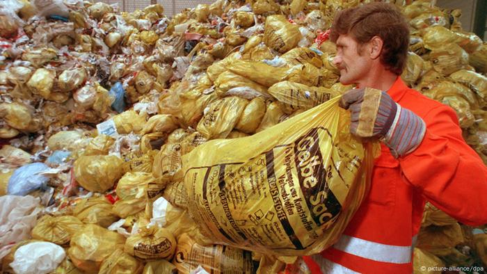 Ein Mitarbeiter einer Entsorgungsfirma stapelt gelbe Säcke mit Kunststoff-Abfällen auf eine riesige Halde (Foto: dpa)
