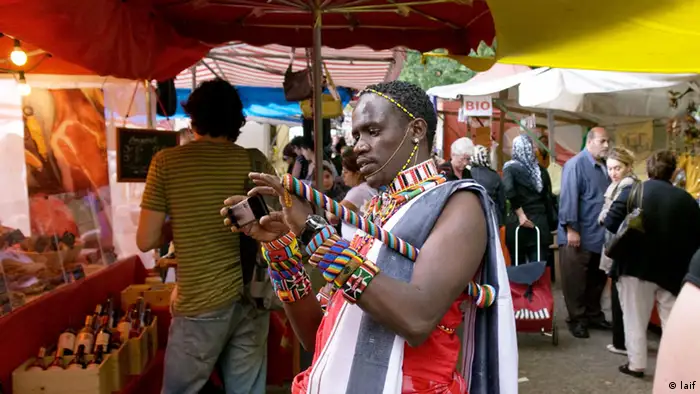 Afrikaner mit ursprünglichem Stammesschmuck und Kamera auf europäischen Markt
