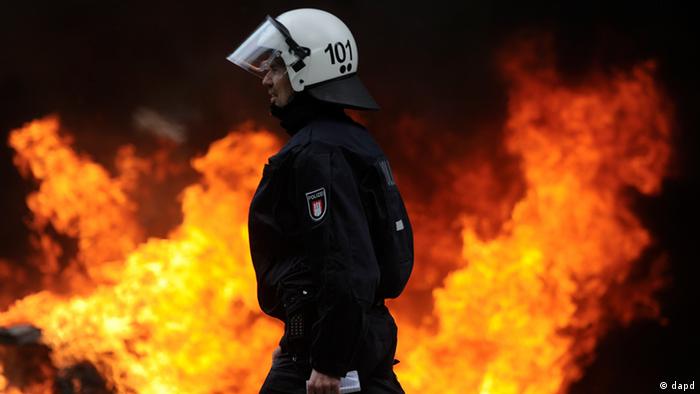Polizist im Feuerschein beim Aufmarsch von Rechtsextremen in Hamburg (Foto: Axel Heimken/dapd)