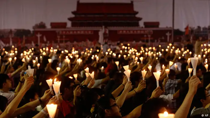 People hold up lit candles during a candlelight vigil at Hong Kong's Victoria Park Monday, June 4, 2012 to mark the 23rd anniversary of the Chinese military crackdown on the pro-democracy movement in Beijing. The background shows a picture taken from Beijing's Tiananmen Square in 1989. (Foto:Kin Cheung/AP/dapd)